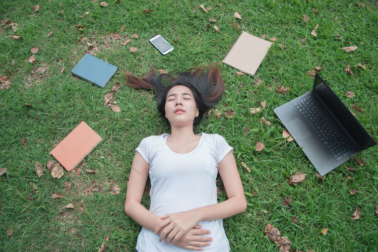 High angle view of young woman lying on field