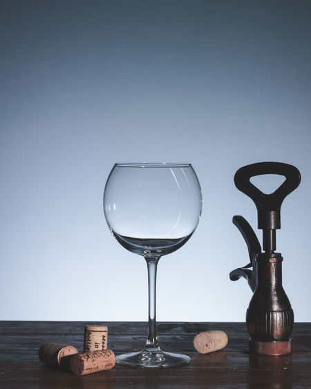 Close-up of wineglass and bottle opener on table