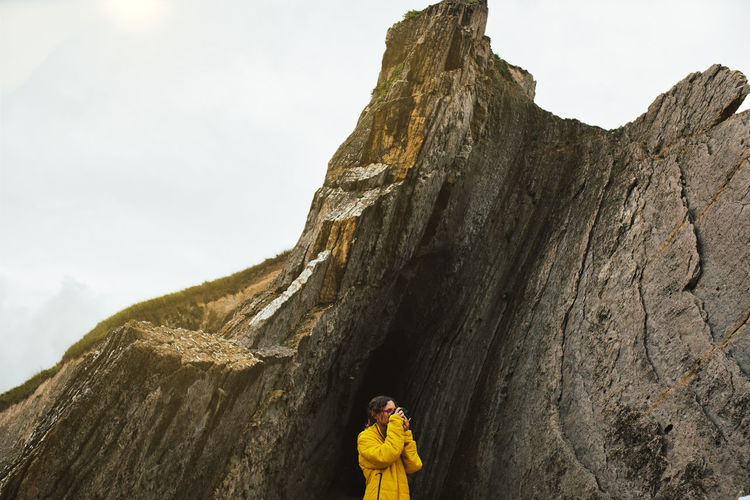 Low angle view of woman on rock against sky