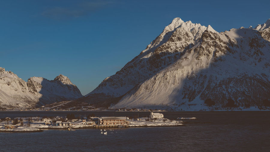 Scenic view of snowcapped mountains by sea against sky
