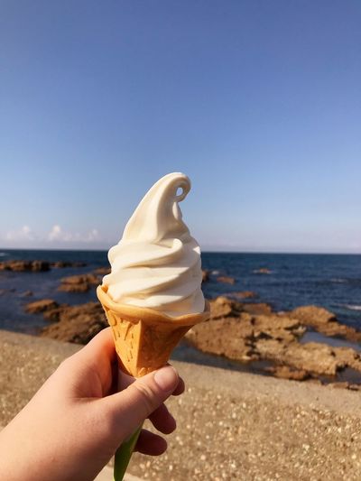 Hand holding ice cream cone on beach