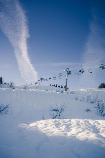 Scenic view of snow covered field against sky and ski lift