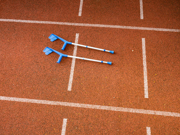 Forearm crutches on red running track on stadium. run lines on front tracks