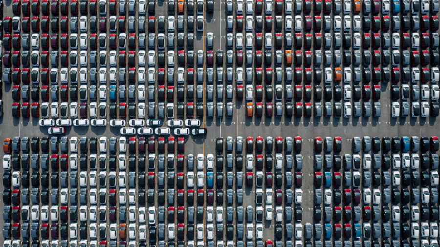 Aerial top view rows of new cars parked in distribution center on car factory.