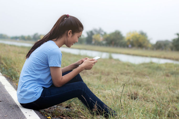 Side view of young woman sitting on field