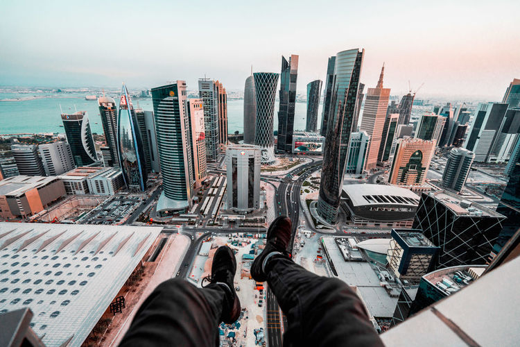 Low section of man sitting on terrace against cityscape