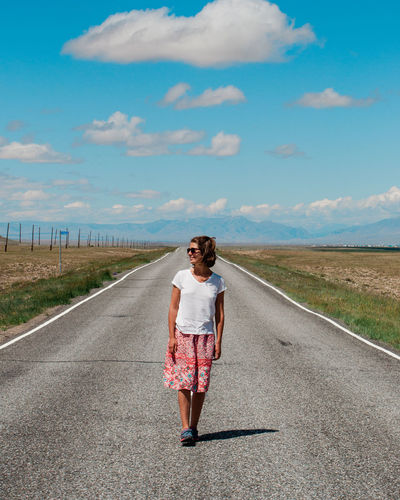 Full length of woman walking on road against sky