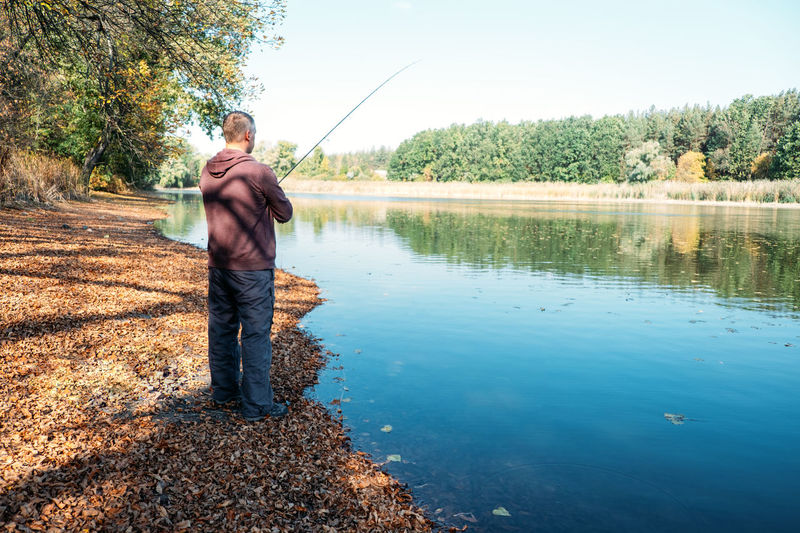 Fisherman with spinning rod on the autumn lake. fisherman with spinning in his hands catching fish
