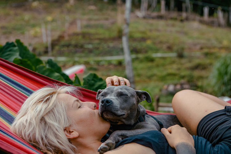 Woman with dog laying in a hammock