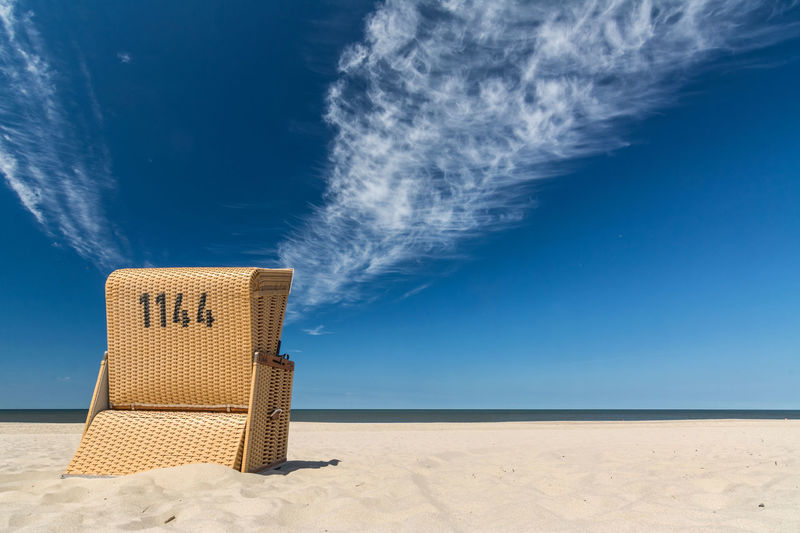 Hooded beach chair at beach against clear blue sky
