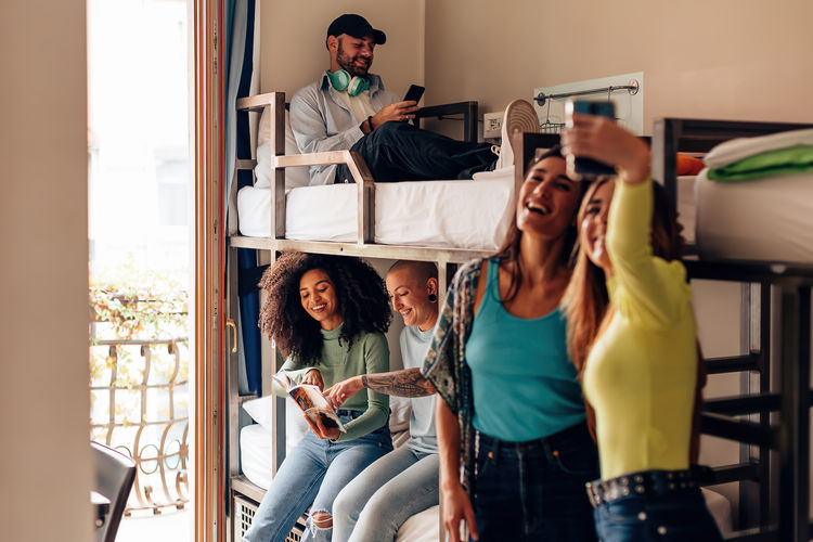 Backpackers lifestyle in youth hostel - young people in room with bunk bed - students in dormitory