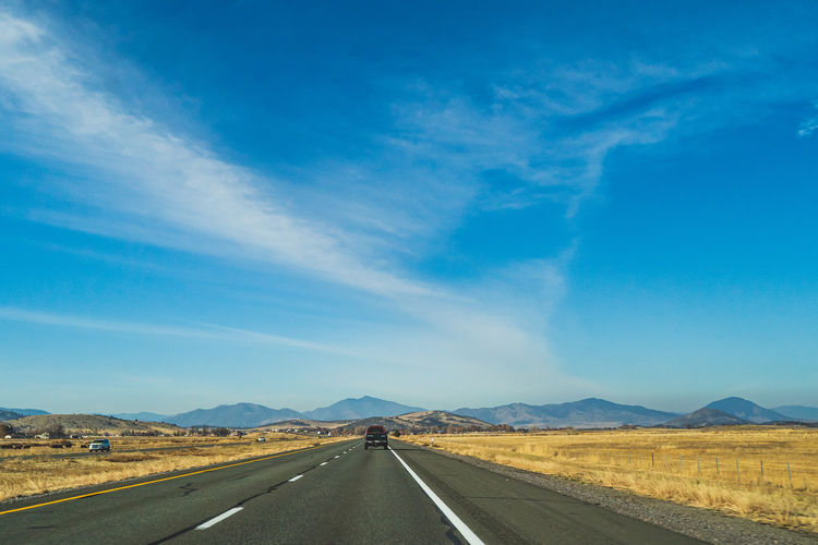 Empty road along landscape against blue sky