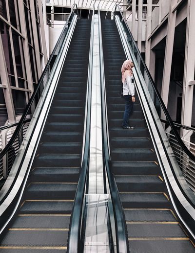 Woman standing on escalator