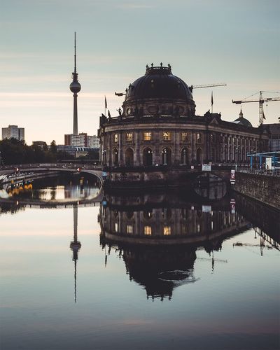 Reflection of historic building and fernsehturm on river in city