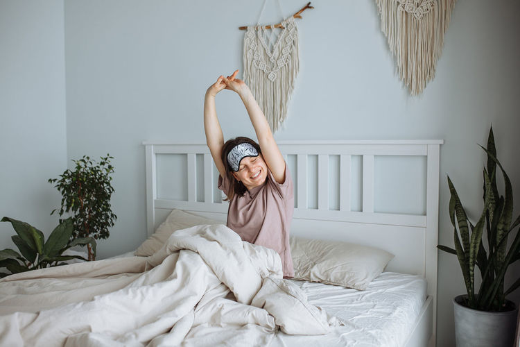 Happy young girl stretching in bed in the morning