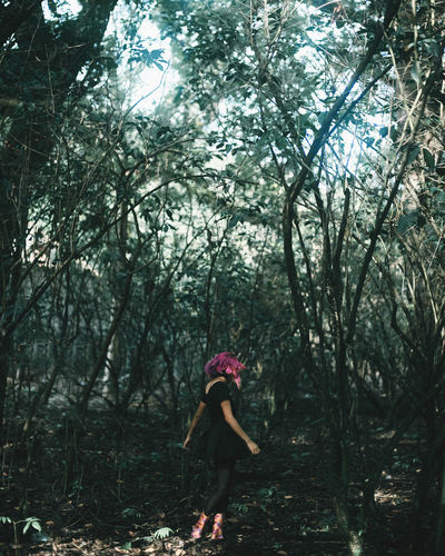 Woman walking against trees in forest
