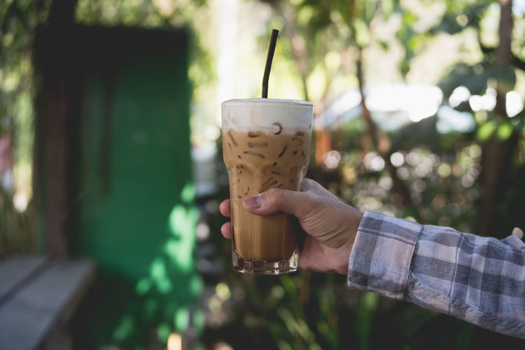 Cropped hand holding iced coffee in glass