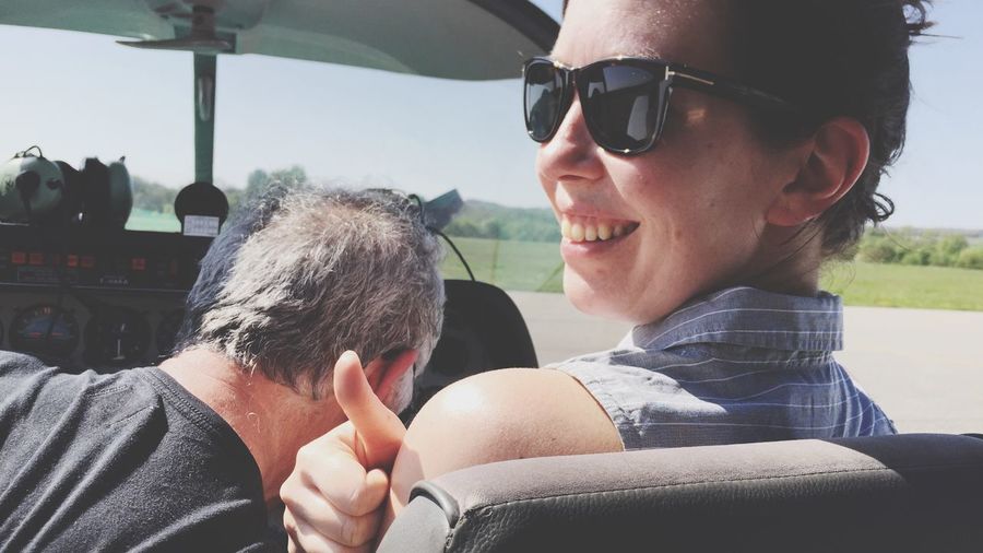 Smiling woman wearing sunglasses gesturing thumbs up while sitting in golf cart
