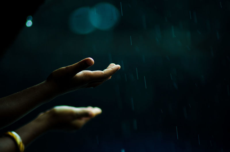 Cropped hands reaching for raindrops