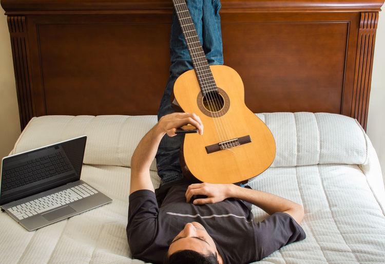 Full length of man playing guitar at home