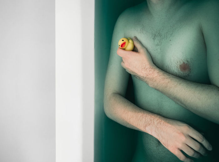 Midsection of shirtless man in bathtub
