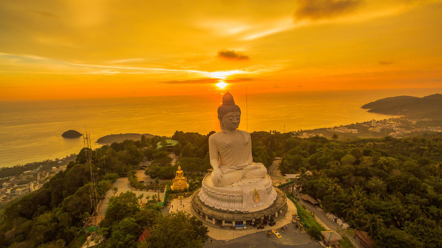 Statue by temple against sky during sunset