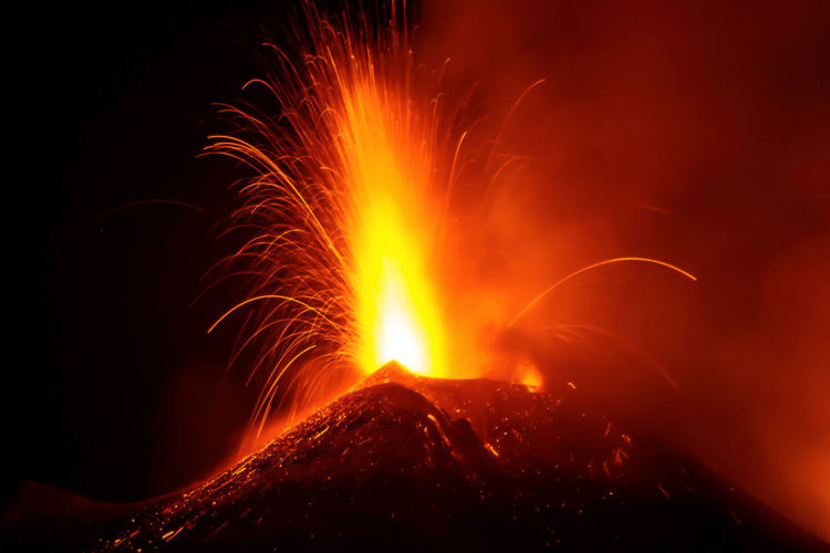Etna volcano during eruption in sicily with great lava explosion from crater and lava flow at night