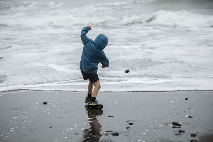 Child skipping rocks on pacific ocean