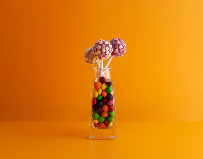 Close-up of multi colored candies against orange background