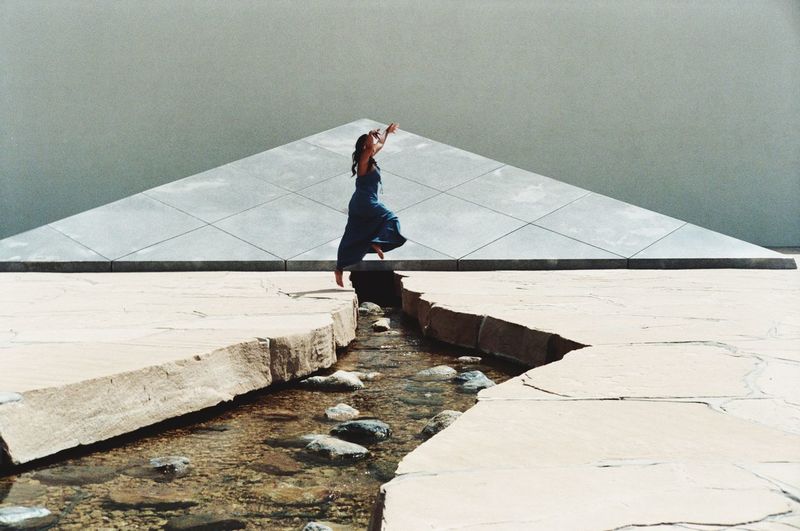 Digital composite image of woman dancing on stream over cracked land