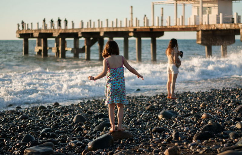 Mother with child girl at the sea beach on sunset