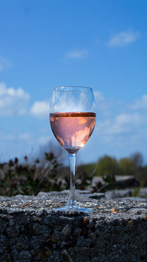 Close-up of wineglass on rock against sky