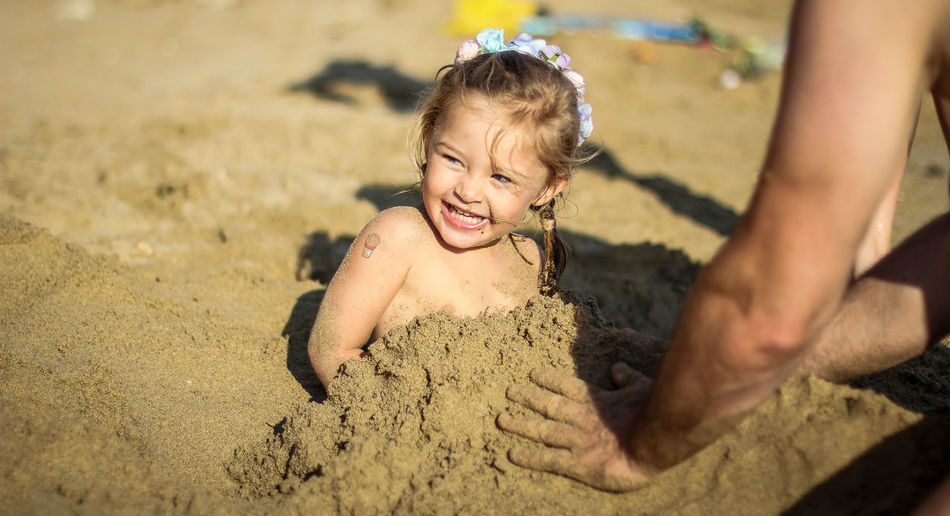 Cute girl buried under sand at beach