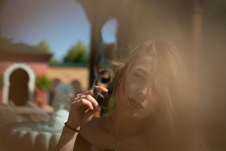 Portrait of woman holding film reel against sky