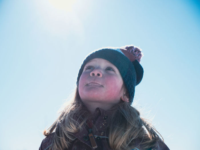 Girl standing outdoors in winter on blue sunny background. portrait. looking away.