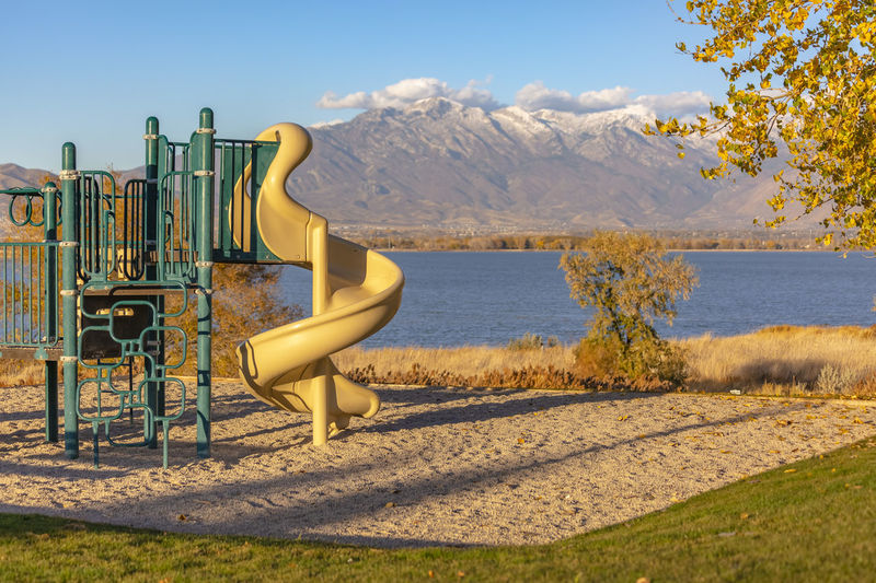 Scenic view of playground by lake against sky