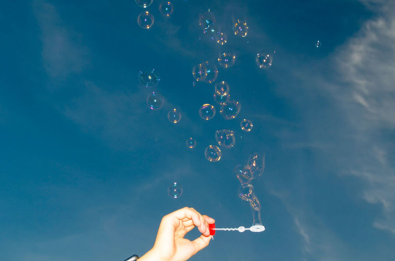 Low angle view of person making bubbles against sky