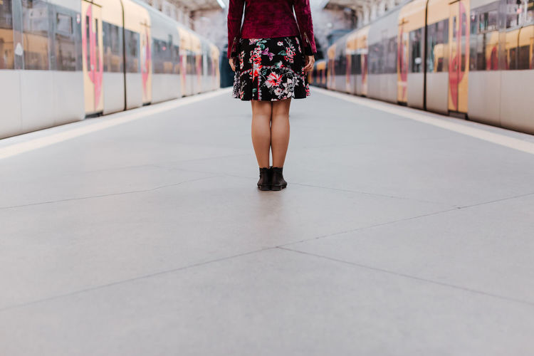 Low section of woman standing on railroad station platform