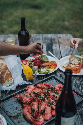Women with picnic table dinner of spot prawns, heirloom tomato salad, wine