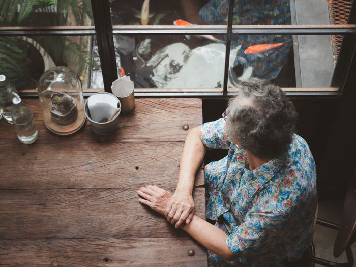 Senior woman looking away out of windows while sitting on chair in a cafe shop. 
