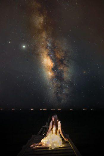 WOMAN AGAINST ILLUMINATED SKY AT NIGHT