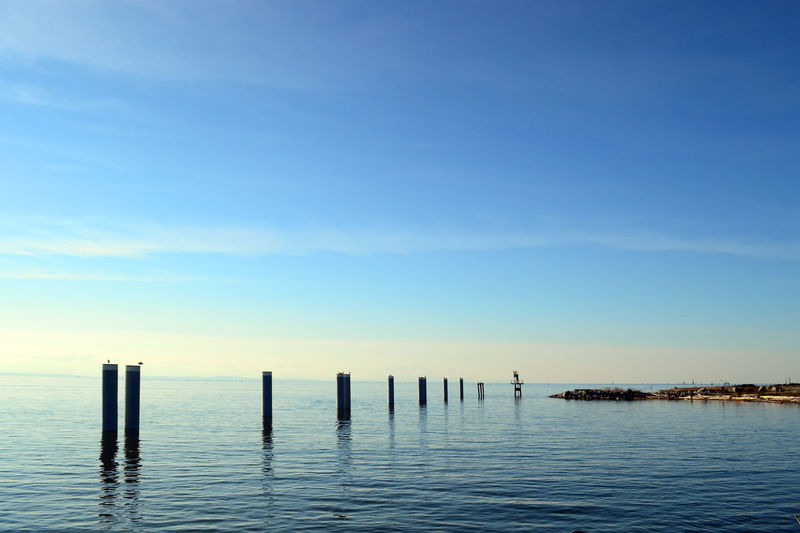 Wooden posts in sea against sky in stivenson village, vancouver