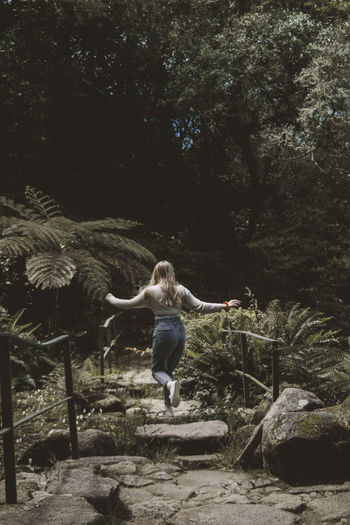 Rear view of woman jumping in forest