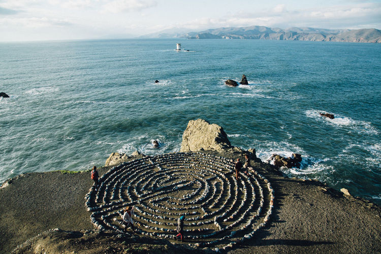High angle view of people taking spiritual journey through meditation labyrinth at coast