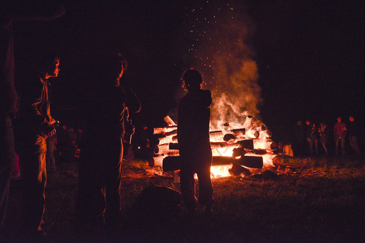 People standing around bonfire at night