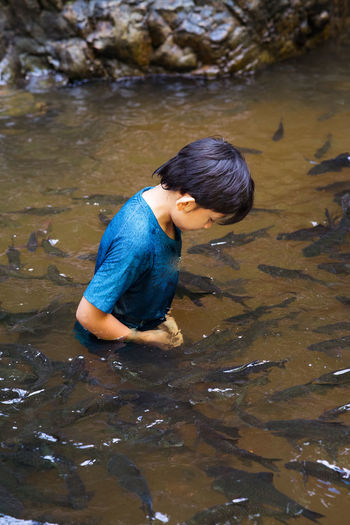 High angle view of boy in standing in lake water