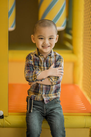 Cute smiling boy with arms crossed sitting on outdoor play equipment