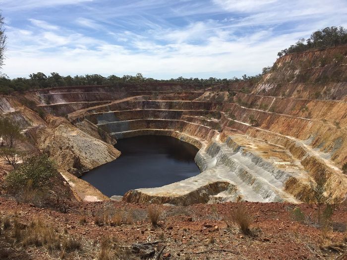 High angle view of open gold mine against sky