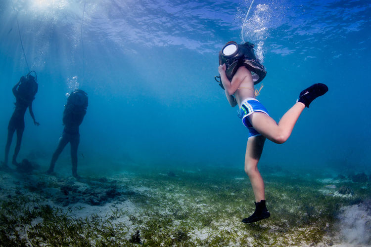 Three people standing undersea with diving equipment