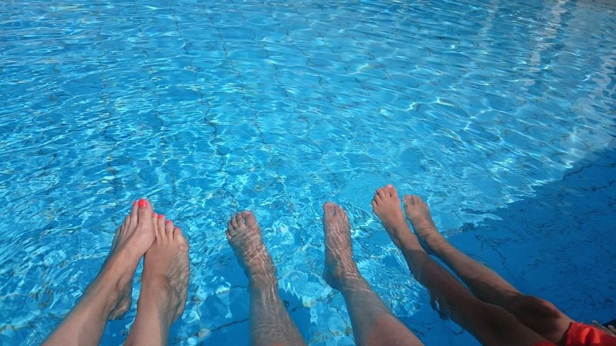 Low section of woman with kids in swimming pool during summer